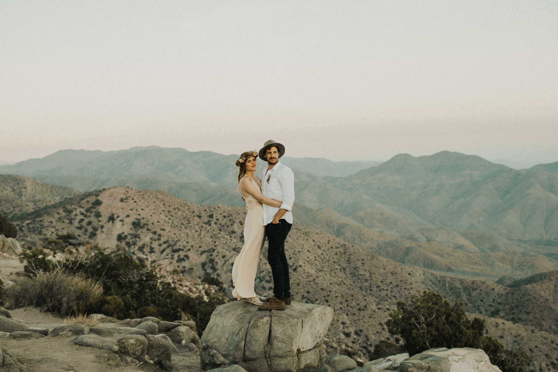 A couple is standing on a rock after their Joshua Tree elopement.