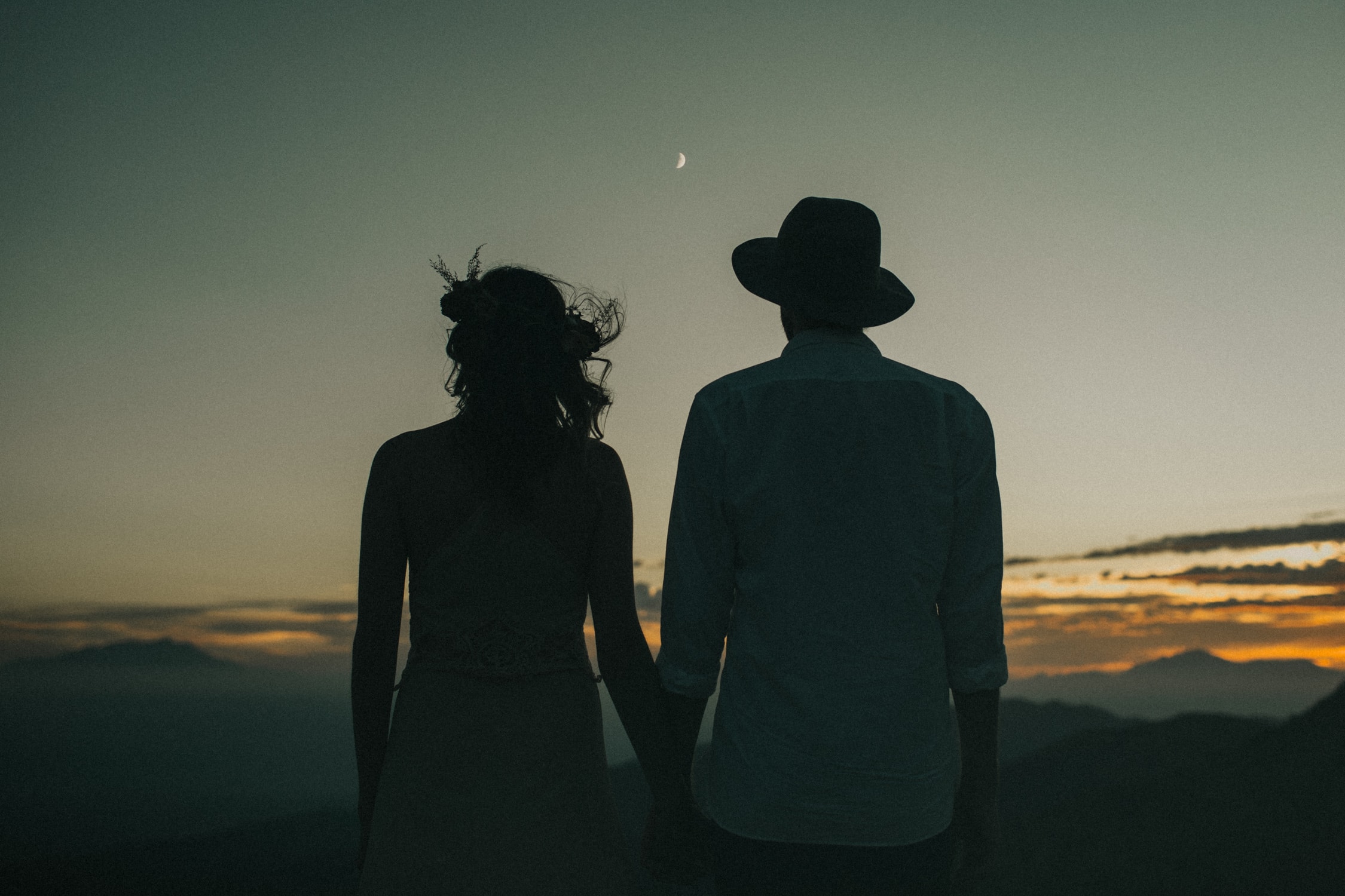A couple is holding hands in front of the sunset during their elopement in Joshua Tree.