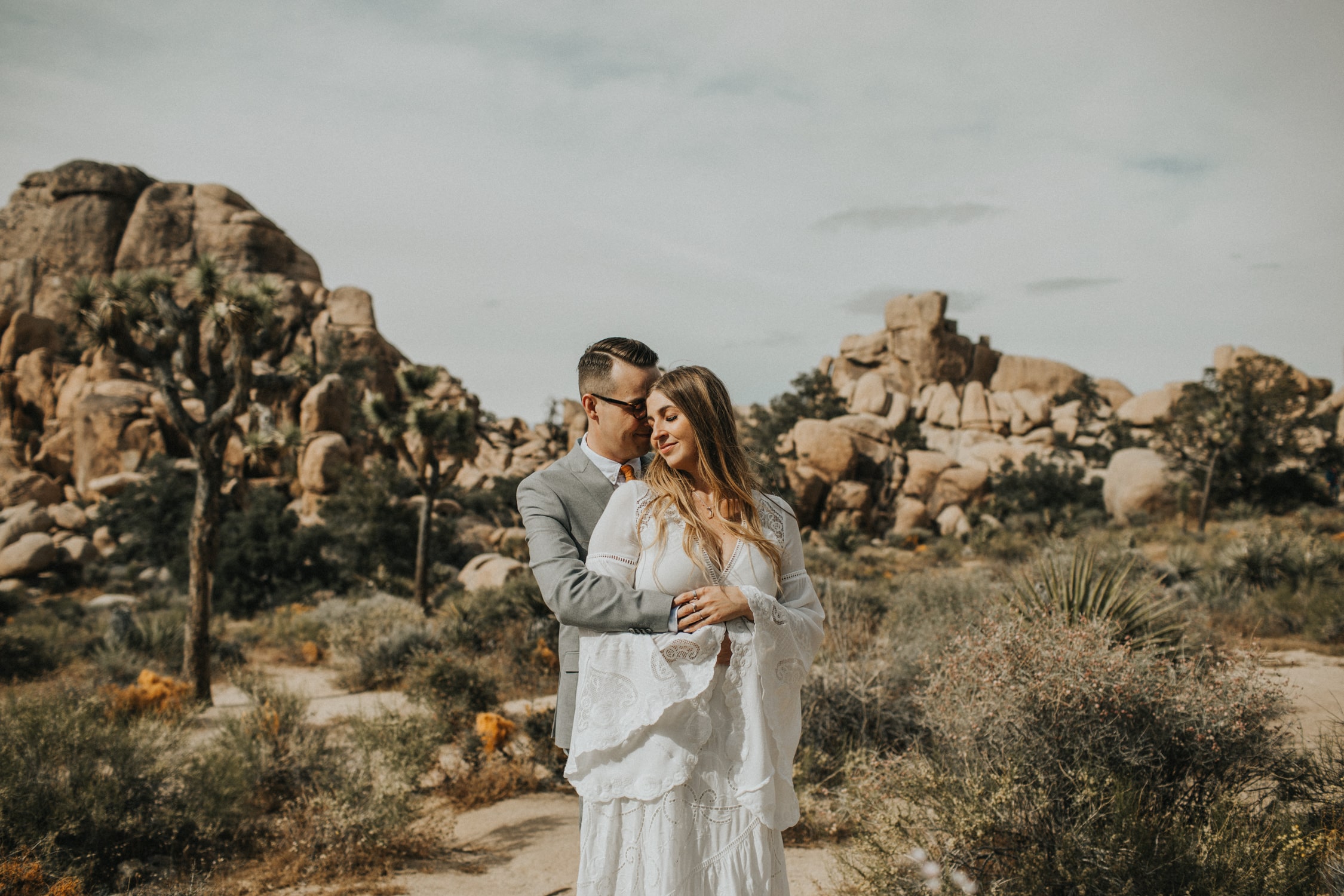 A couple is hugging in front of Cap Rock during their elopement in Joshua Tree National Park.